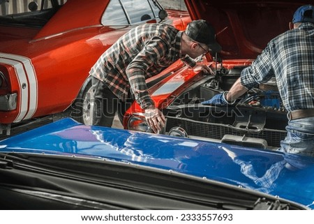 Two Caucasian Professional Classic Cars Mechanics Looking Under Muscle Car Hood