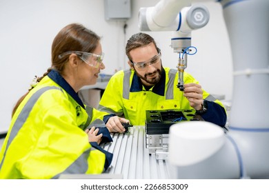 Two Caucasian professional technician or engineer workers sit in workplace and help to check and work with quality control the robotic arm machine in factory together and look happy during work. - Powered by Shutterstock