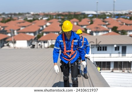 Two Caucasian roofer men with safety gears walking on industry metal roof after finishing work on height