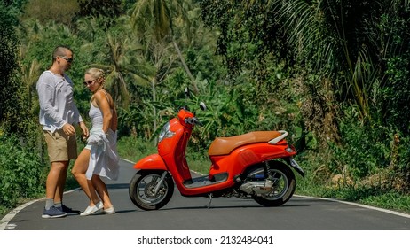 Two Caucasian Tourist Woman Man Dance Near Scooter. Love Couple On Red Motorbike In White Clothes, Sunglasses On Forest Road Trail Trip. Dancing Road. Motorcycle Rent. Asia Thailand Ride Tourism.