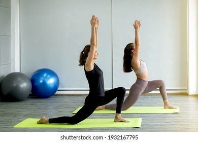 Two Caucasian women exercise doing the yoga pose stretching at home, healthy lifestyle concept.