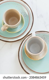 two ceramic cups and plates on white marble table
