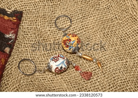 two ceramic keychains in ball form decorated by ancient turkish pattern on burlap background