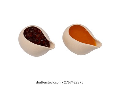 Two ceramic pourers sit side-by-side, one filled with dark boba pearls and the other with a smooth, golden-orange fruit sauce.