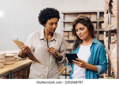 Two ceramists using a digital tablet while working together in their store. Businesswomen managing a store with handmade ceramic products. Female entrepreneurs running a creative small business. - Powered by Shutterstock - Get 15% off with code: PIKWIZARD15