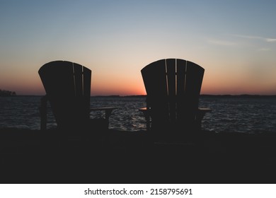 The Two Chairs Against An Ocean During Sunset