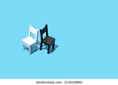 
Two Chairs, Black And White Concept On A Pastel Blue Background. Contrast, Opposites, Disagreement. 