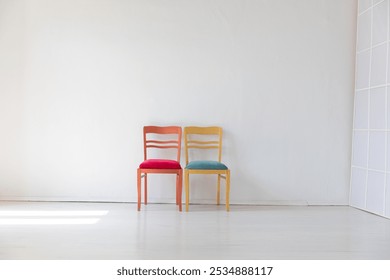 two chairs in the interior of an empty white room with a window