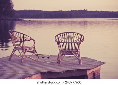 Two Chairs On Dock With Glasses Of Wine