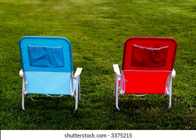 Two Chairs on Grass one red, one blue