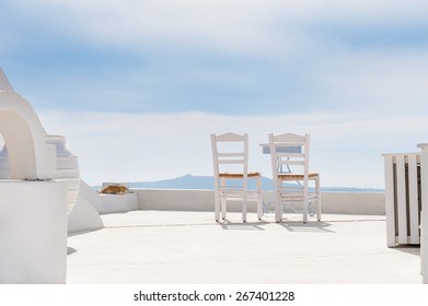 Two Chairs On The Terrace. White Architecture On Santorini Island, Greece. Summer Holidays