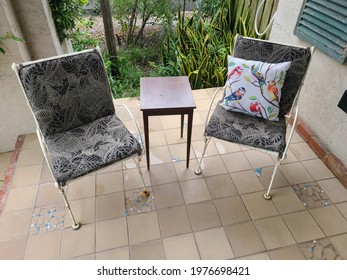 Two Chairs On A Tile Porch With Wooden Table