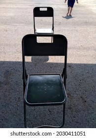 Two Chairs With One Person Walking In The Background