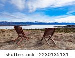 Two chairs vista point overlooking still ice-covered frozen Lake Laberge spring taiga boreal forest landscape of Yukon Territory, YT, Canada