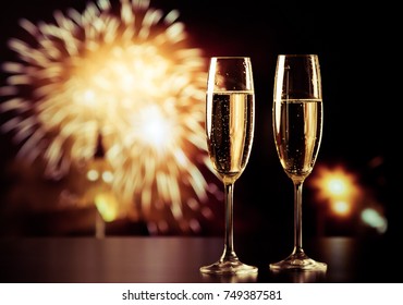 two champagne glasses against holiday lights and fireworks - new year celebration