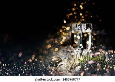 Two Champagne Glasses And Christmas Decoration Over Dark Golden Bokeh Background. New Year And Christmas Luxury Party Celebration. Sparkling New Year 2020 Backdrop Layout Design.