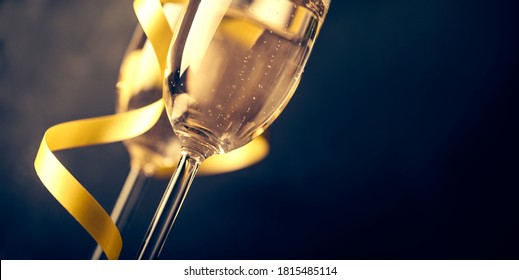 Two Champagne Glasses With Golden Ribbon On Dark Background With Copyspace. Luxury Restaurant Dinner Celebration. Classy Christmas And New Year Holiday Panoramic Design Banner.