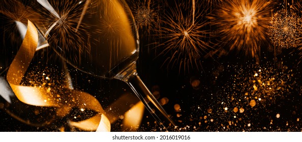 Two Champagne Glasses With Golden Ribbon And Gold Glitter Splash Bokeh On Dark Background. Luxury Restaurant Dinner Celebration. Classy Christmas And New Year Holiday Panoramic Design Banner.