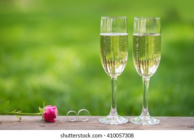 Two Champagne Glasses, Rose And Wedding Rings Outdoor