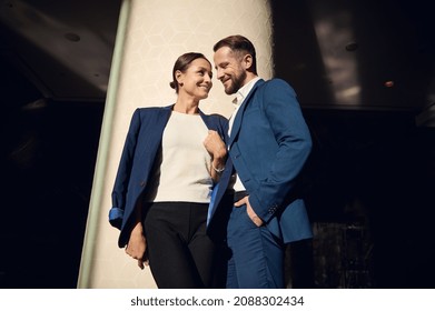 Two Charming Middle Aged People, Business Partners, Colleagues, Flirting Together Standing Close To Each Other In The Lobby Of Luxury Hotel. Love Affairs At Work, People, Business, Intrigues Concept