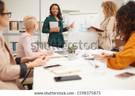 Two charming women making presentation together at businessmeeting in modern office room