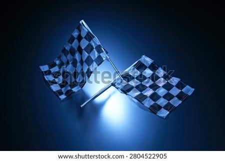 Two checkered racing flags are dramatically lit with a bright blue light against a dark background, creating a sense of excitement and competition.
