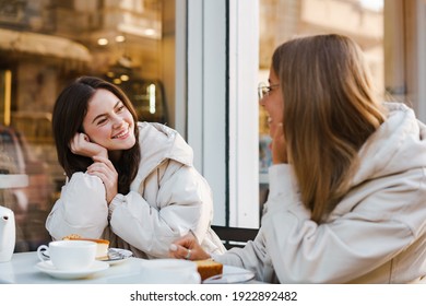 Two Cheerful Attractive Women Friends Having Tea And Cakes At The Cafe Outdoors