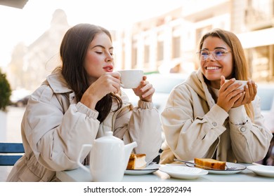 Two Cheerful Attractive Women Friends Having Tea And Cakes At The Cafe Outdoors