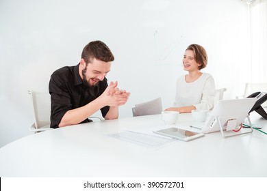 Two Cheerful Attractive Young Business People Talking And Laughing On Meeting In The Office