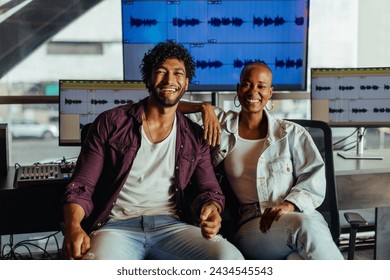 Two cheerful audio engineers share a joyful moment during a break in a contemporary sound recording studio. Their bright smiles and casual attire highlight a relaxed, creative workplace atmosphere. - Powered by Shutterstock