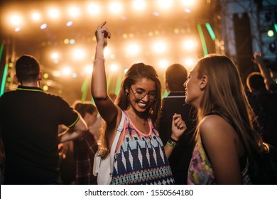 Two cheerful females having a good time at an outdoor festival - Shutterstock ID 1550564180