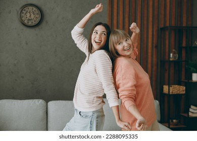 Two cheerful fun cool happy joyful adult women mature mom young kid wearing casual clothes dance near gray sofa couch stay at home flat rest relax spend free spare time in living room. Family concept - Powered by Shutterstock