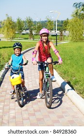 Two Cheerful Kids Riding Bikes In Park