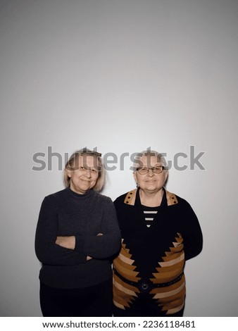 Similar – laughing twin sisters in front of the wall with red and blue green coat