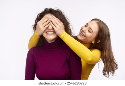 Two cheerful LGBT women enjoying a playful moment together, one playfully covering the other's eyes while both are laughing joyfully. - Powered by Shutterstock