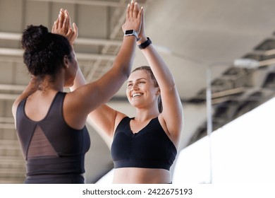 Two cheerful plus-size women in fitness wear giving high five after a workout. Women athletes during fitness training outdoors giving high five. - Powered by Shutterstock