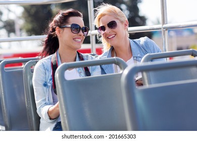 two cheerful tourists enjoying open top bus tour in the city