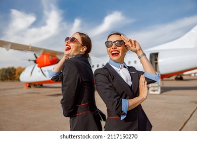 Two cheerful women stewardesses standing outdoors at airport