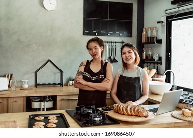 Two cheerful young asian bakery chef in the kitchen inside bakery shop. - Powered by Shutterstock