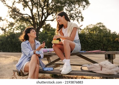 Two cheerful young caucasian women have relaxing lunch break outdoors. Girlfriends wear casual clothes on summer day. Lifestyle concept - Powered by Shutterstock