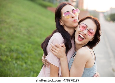 Two Cheerful Young Women Walking On The Street And Hugging At Sunset. Best Friends