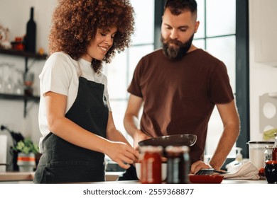 Two chefs collaborate in a modern kitchen, cooking a gourmet meal with fresh ingredients. They follow a recipe, showcasing their culinary skills and teamwork - Powered by Shutterstock