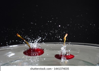 two cherries at high speed falling in the water with black background