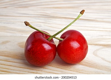 Two cherry berries isolated on wooden background