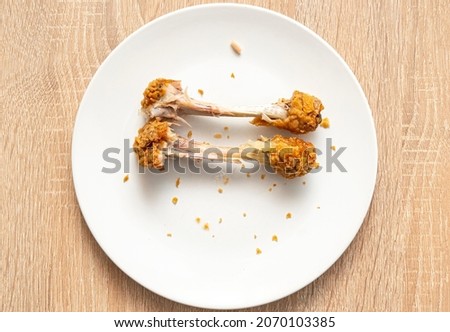 Two chicken bones as left over on white plate. Unhealthy fast food, chicken legs, top view ストックフォト © 