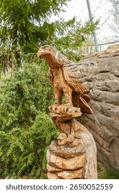 Two chicks of an eagle or a kite sit in the nest and the mother guards them. Wood sculpture - wood carving, animals