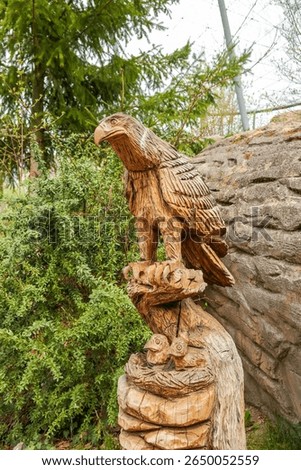 Two chicks of an eagle or a kite sit in the nest and the mother guards them. Wood sculpture - wood carving, animals