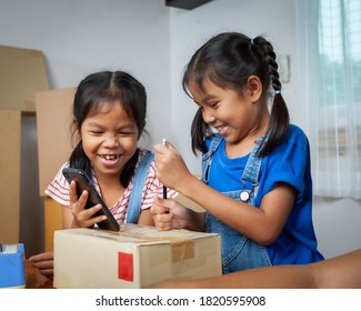 Two child girls helping parent to write customer address into the box to prepare delivery box for the online customer with fun and happy