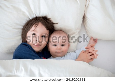 Similar – Baby girl reading book with family in the bed