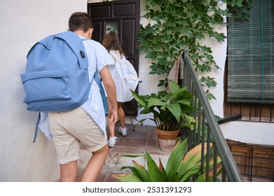 Two children with backpacks entering a home after school, symbolizing education, routine, and family life in a cozy setting. - Powered by Shutterstock